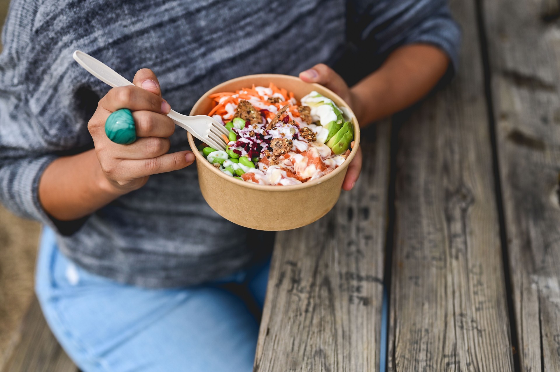Poke bowl with raw salmon in take out paper container.